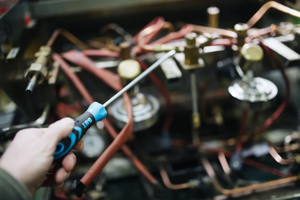 Técnico reparando con desarmador el interior de una máquina, un ejemplo de mantenimiento correctivo