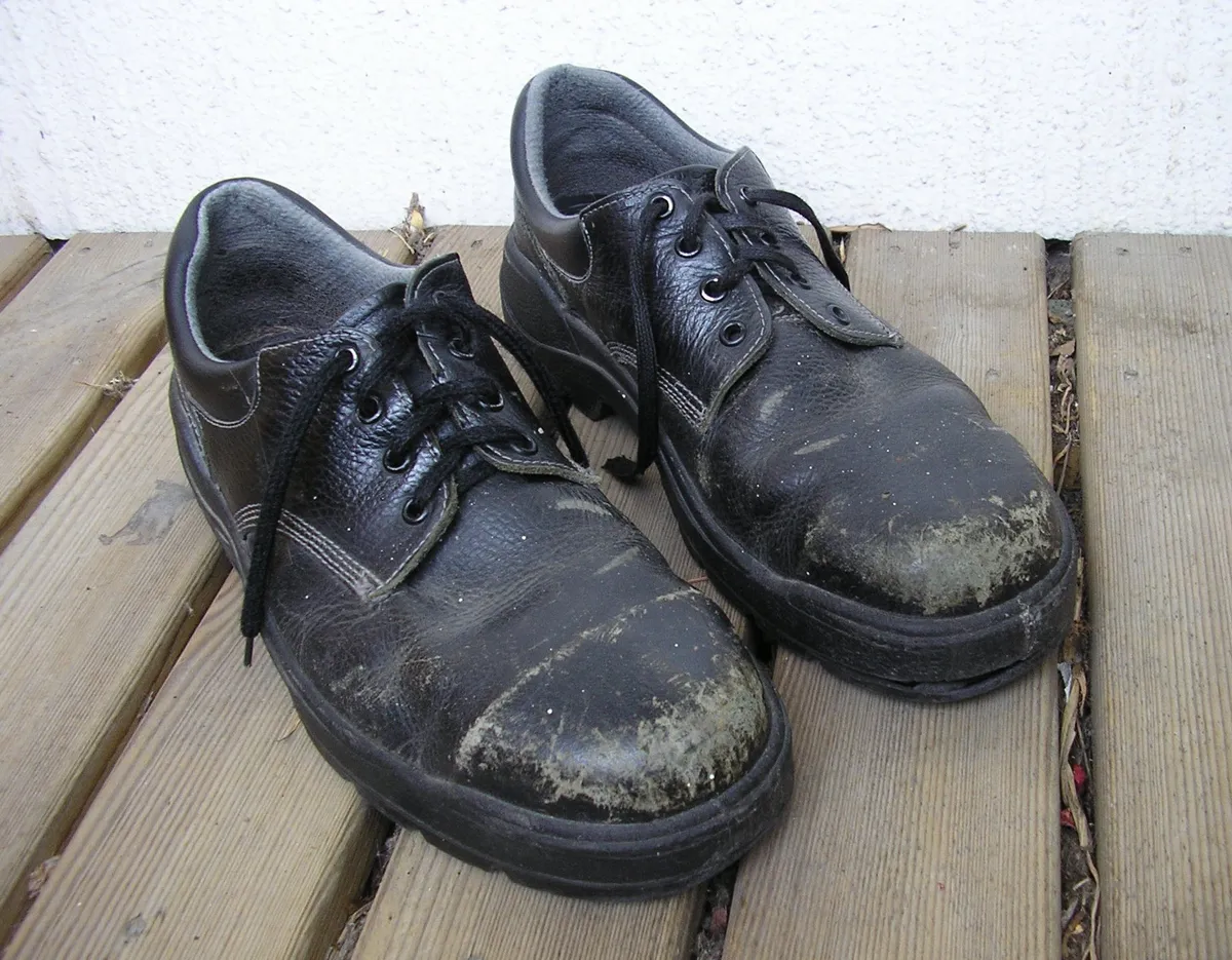 Par de botas de seguridad con casquillo, gastadas por el trabajo