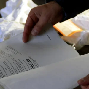 Manos revisando el manual y la lista de verificación de mantenimiento de un equipo