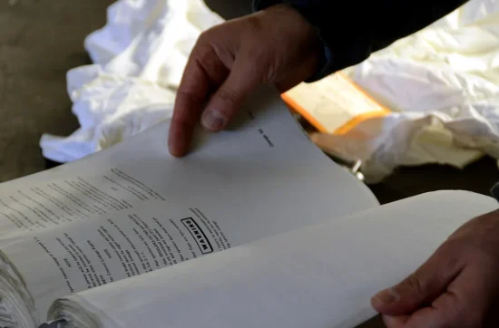 Manos revisando el manual y la lista de verificación de mantenimiento de un equipo